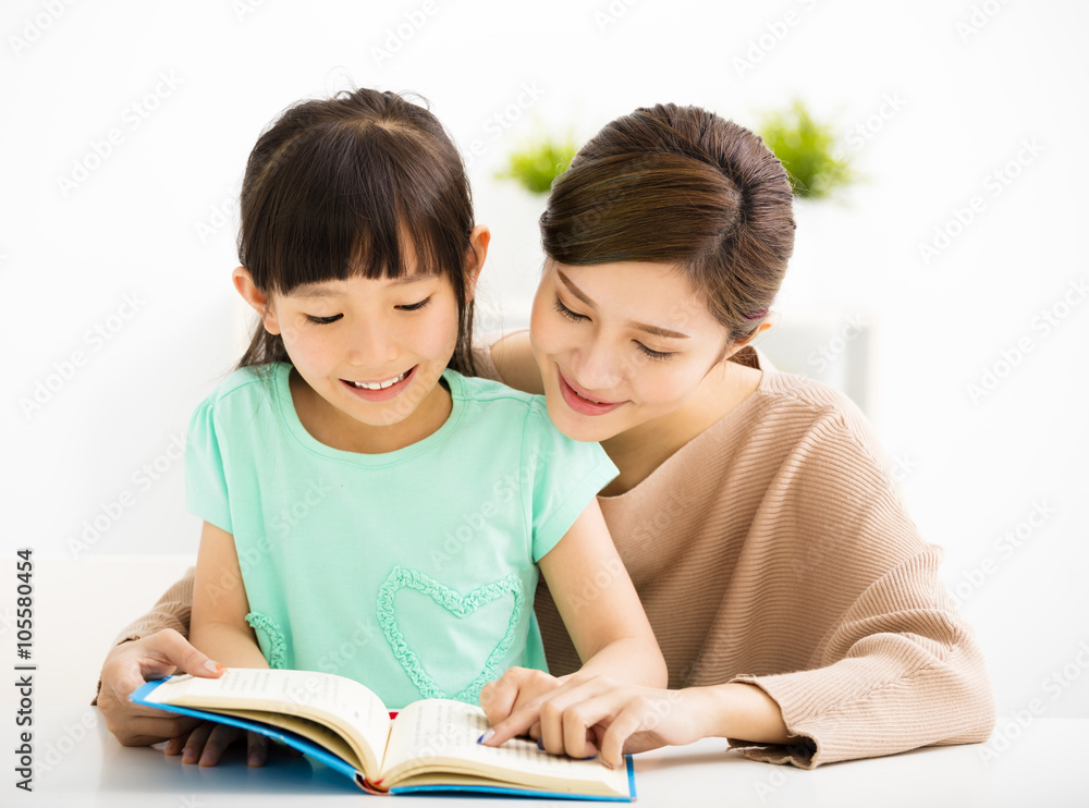 happy Little girl looking at book with her mother happy Little girl looking at book with her mother