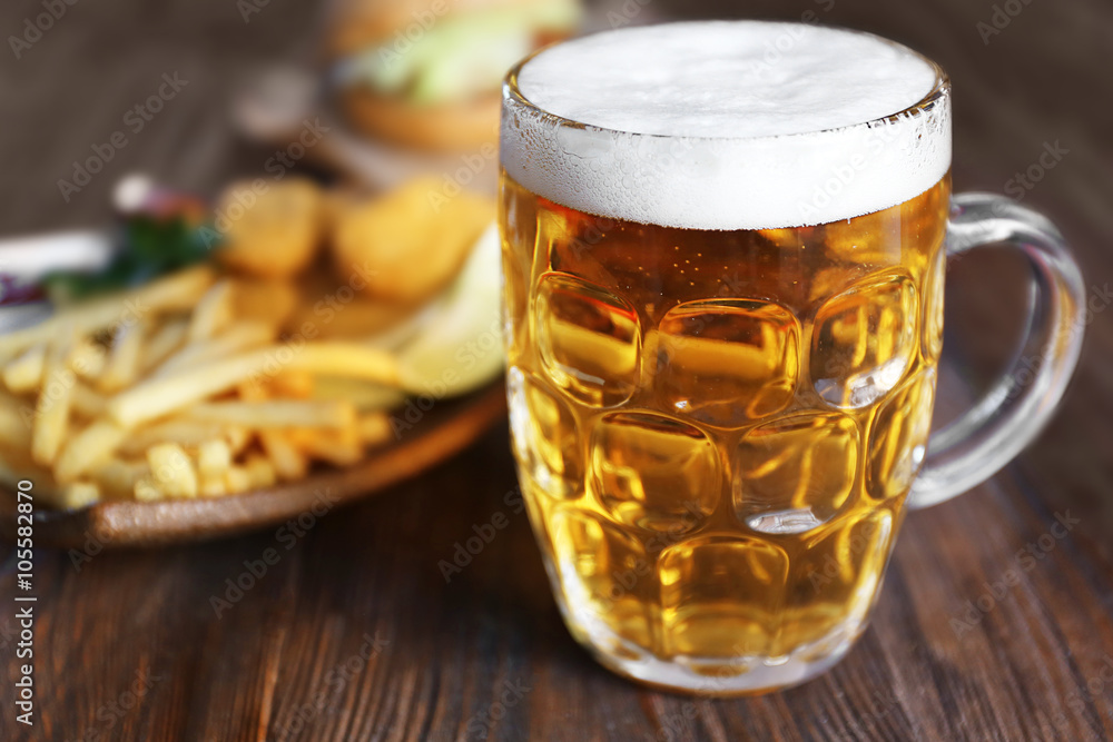 Glass mug of light beer with French fries on dark wooden table, close up Glass mug of light beer with French fries on dark wooden table, close up