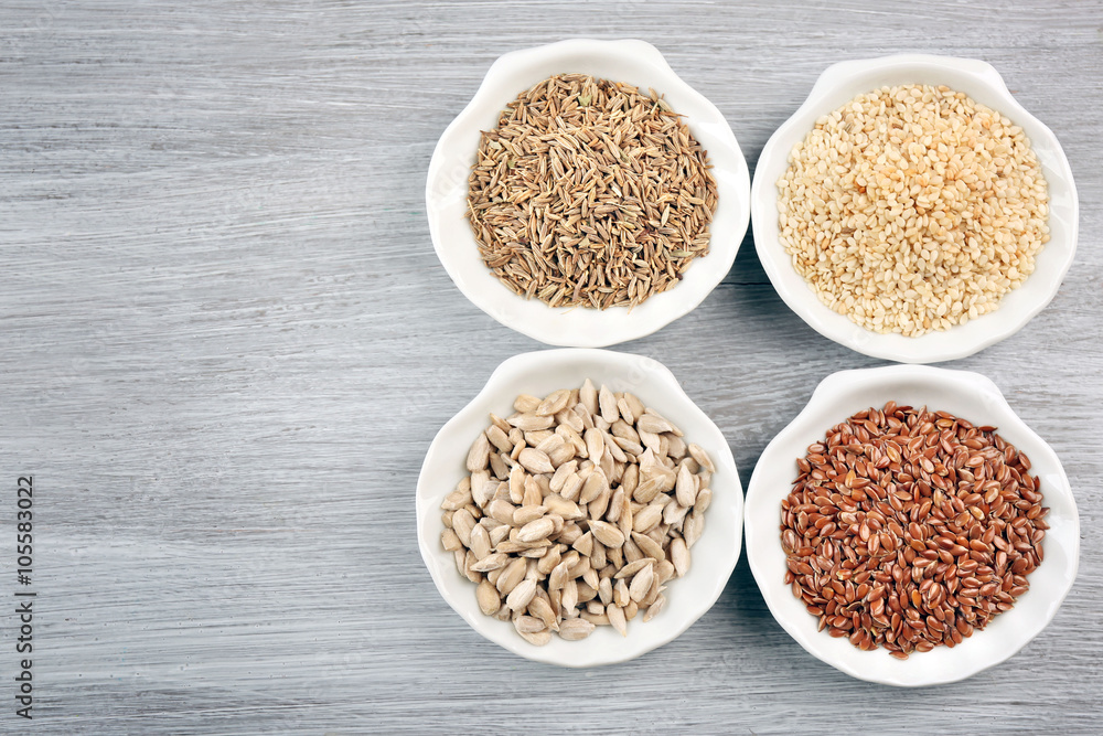 Different kinds of seeds in bowl on wooden table Different kinds of seeds in bowl on wooden table
