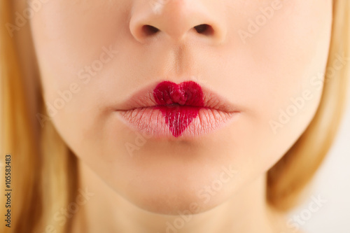 Sexy lips with cherry-coloured heart shape paint  closeup