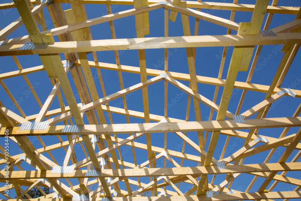 Construction of wooden roof under blue sky on house under coonstruction Construction of wooden roof under blue sky on house under coonstruction