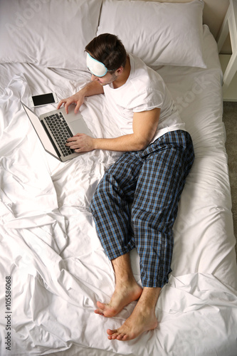 Young man lying in bed with...