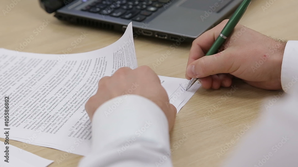 Businessman signs documents at the table Businessman signs documents at the table