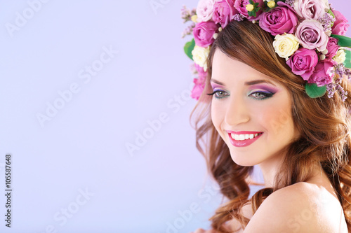 Beautiful young woman wearing floral headband on a purple background