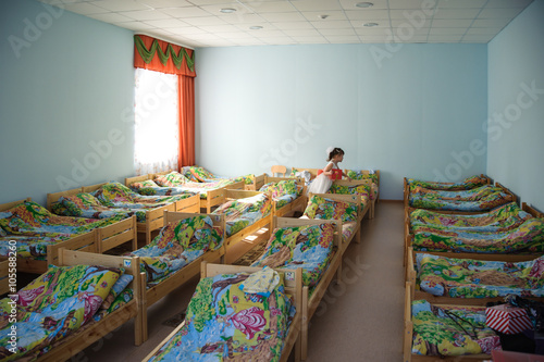 Tableau sur toile In a room with lots of beds is a girl in one of them