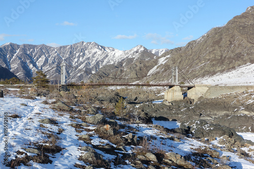 Suspension bridge Oroktoysky through the frozen Katun  river among mountains, Altai, Russia
 photo