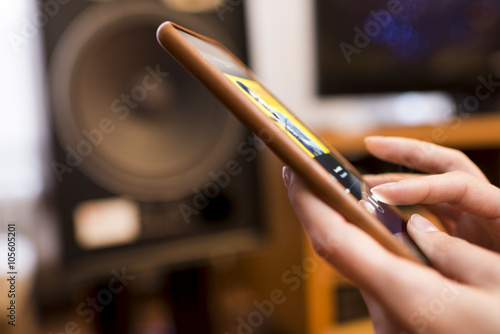 Woman listening music from a smart-phone connected. Speaker bluetooth