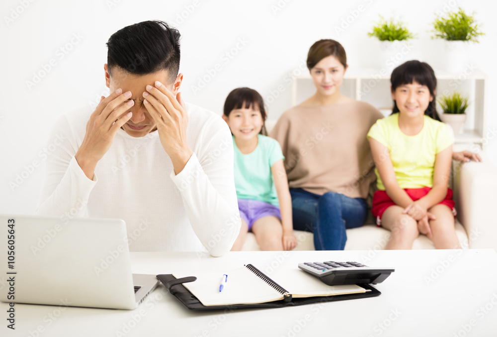stress man calculating bills while family sitting on the sofa stress man calculating bills while family sitting on the sofa