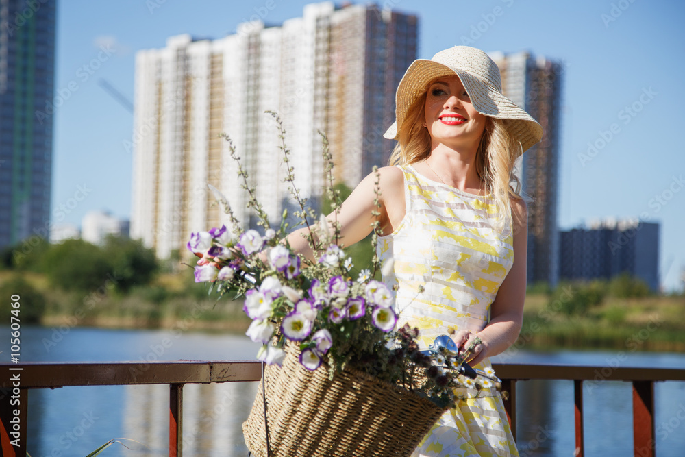 Beautiful sweet blonde woman walks with bicycle near skyscrapers