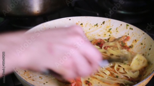 Preparing pasta spaghettin with shrimps, stirring in a pan photo