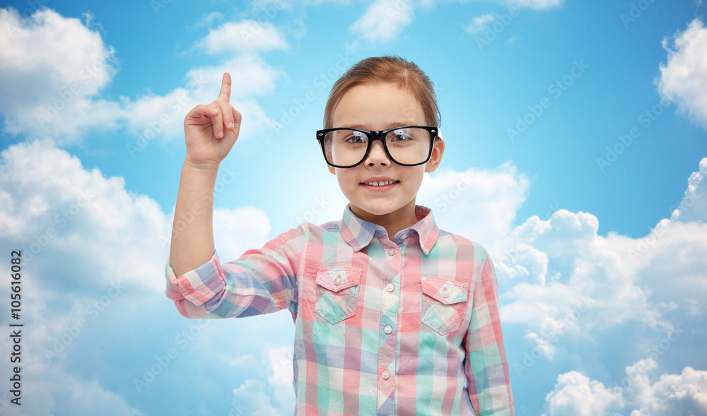 happy little girl in eyeglasses pointing finger up