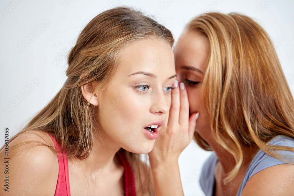 happy young women whispering gossip at home happy young women whispering gossip at home