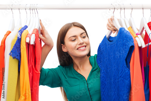 happy woman choosing clothes at home wardrobe