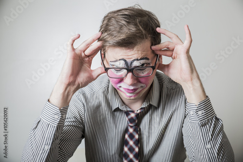 young businessman in the make-up clown, wrapt in thought photo