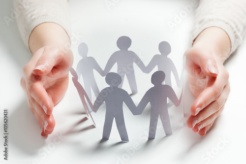 Foto Paper people surrounded by hands in gesture of protection