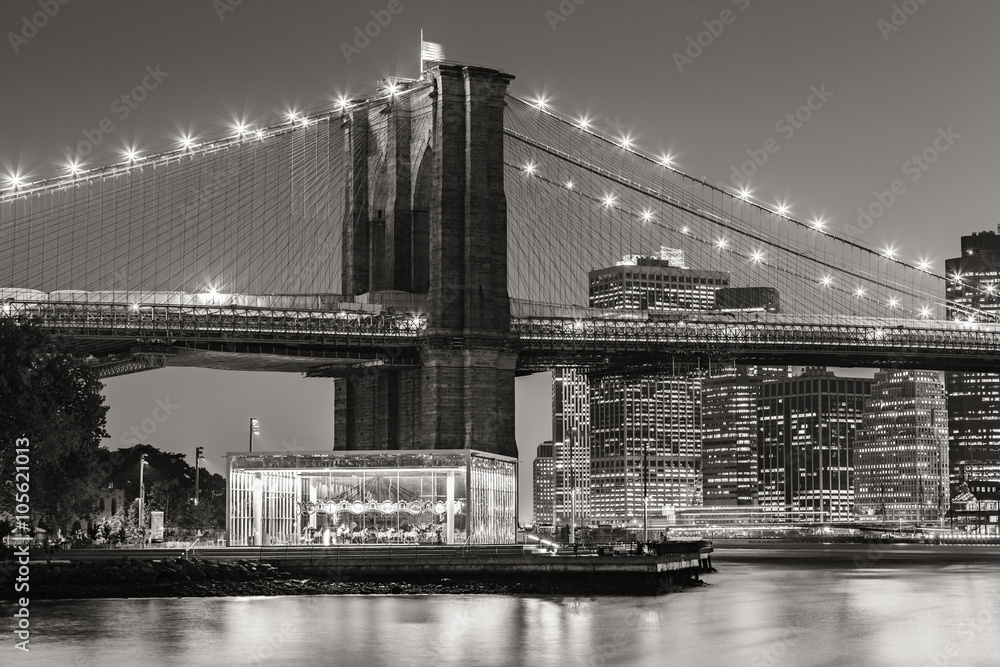 Black and White of  Brooklyn Bridge Tower at twilight with carousel and skyscrapers of Lower Manhattan. Financial District. New York City