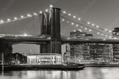 Black and White of Brooklyn Bridge Tower at twilight with carousel and skyscrapers of Lower Manhattan. Financial District. New York City