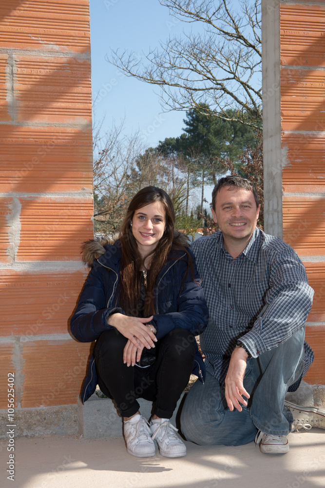 Cheerful couple sitting inside house under construction
