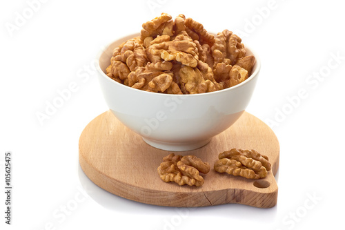 Walnuts in white bowl on wooden board. Isolated on white background.