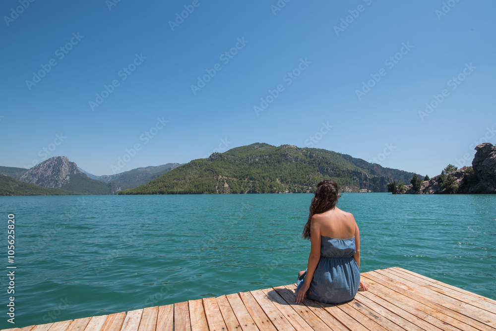 Pretty woman sitting alone on the pier