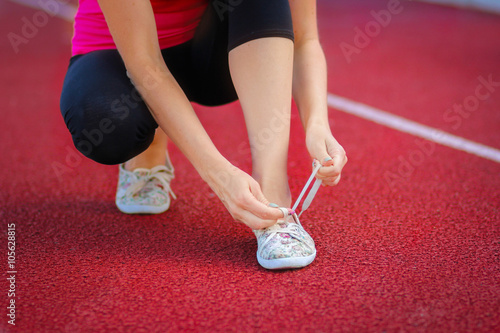 Running shoes - closeup of woman tying shoe laces. Female sport fitness runner getting ready for jogging outdoors © roggozub