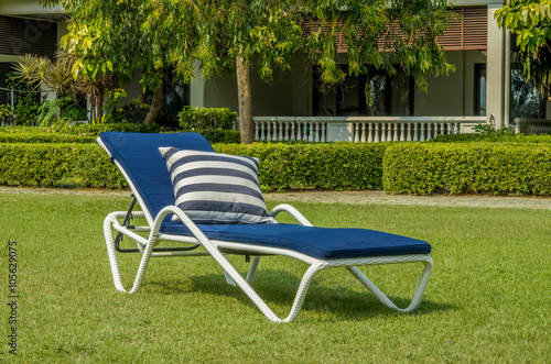 Fotografia, Obraz Blue cushion on white rattan sun lounger in the green garden