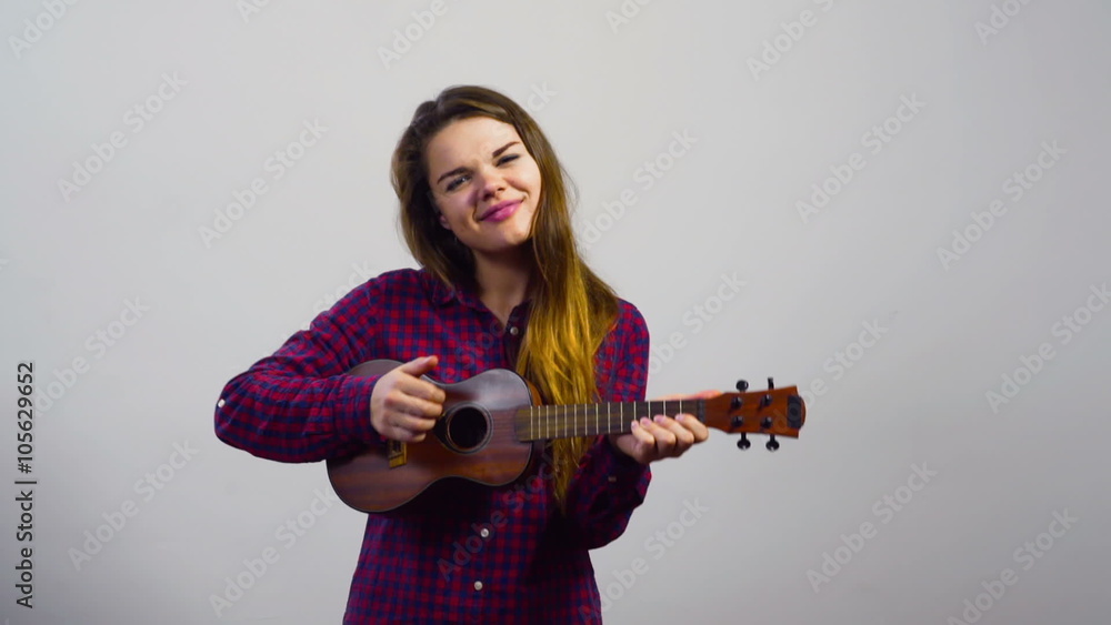 young girl playing ukulele in front of white wall young girl playing ukulele in front of white wall