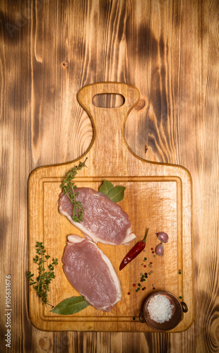 Fresh meat steaks on light wooden cutting board. Toned