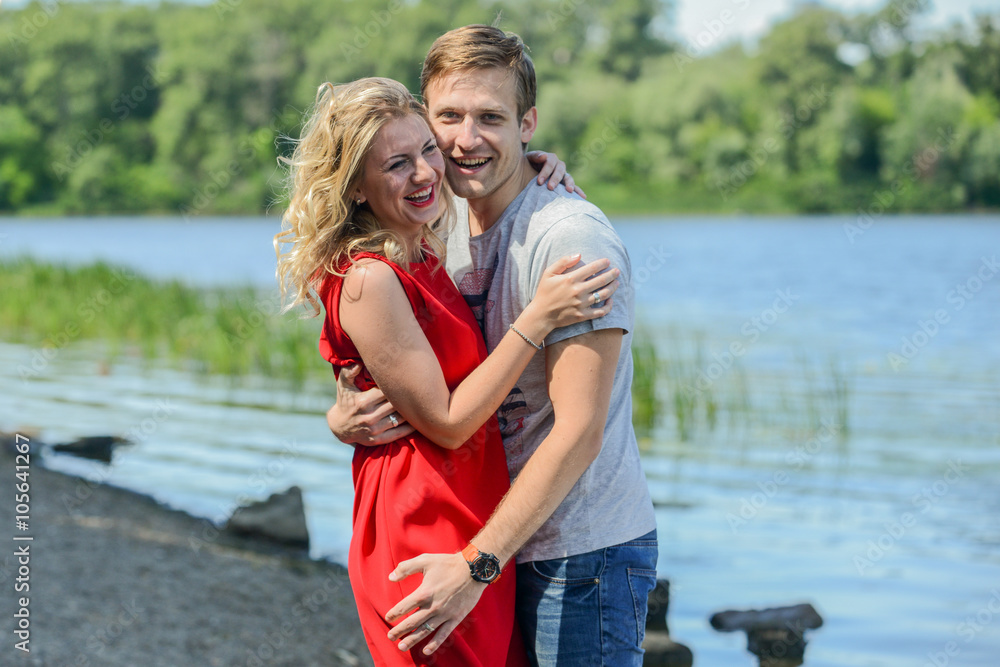 Young happy couple hugging and laughing on river background Young happy couple hugging and laughing on river background