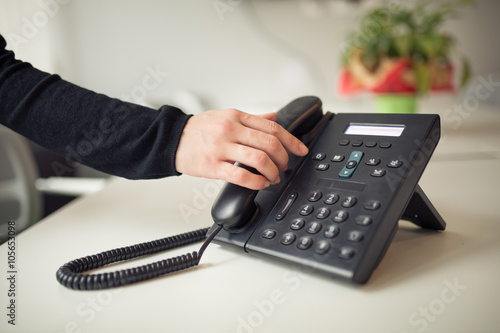Answering phone call.Phone ringing.Good or bad news.Business failure.Customer service help center.Secretary answering phone in her office.Desk table office phone and womans hand picking up