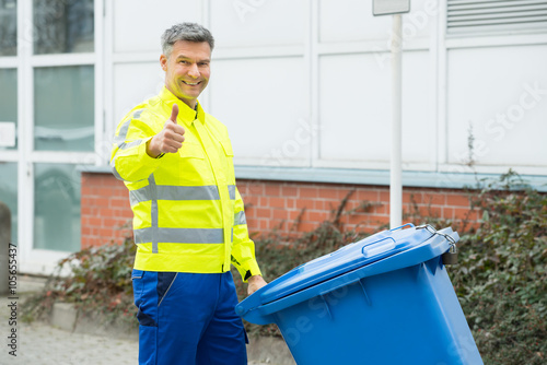 Fotografie Working Man Holding Dustbin On Street