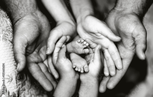 Руки отца, матери, дочери, держать ножки малыша. Дружелюбная счастливая семья, вместе (черно-белое фото)