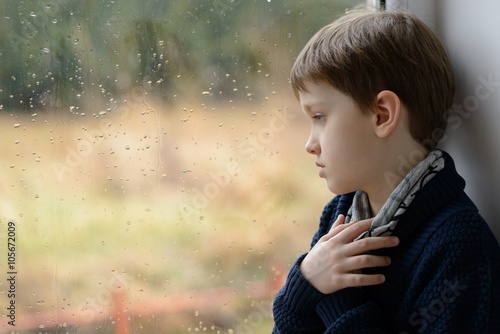 thoughtful little boy looking through the window.