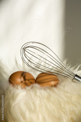 Two orange speckled eggs with whisk on the white fur