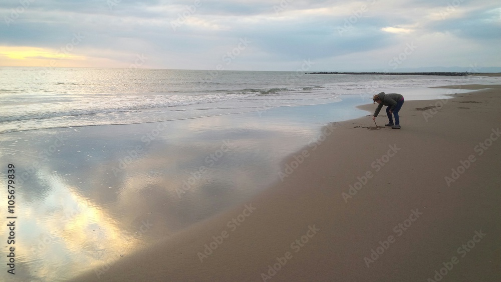 Naklejka premium ragazza che scrive sulla sabbia