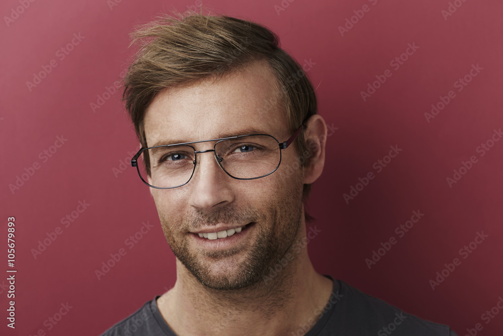Obraz premium Smiling man in spectacles in red studio