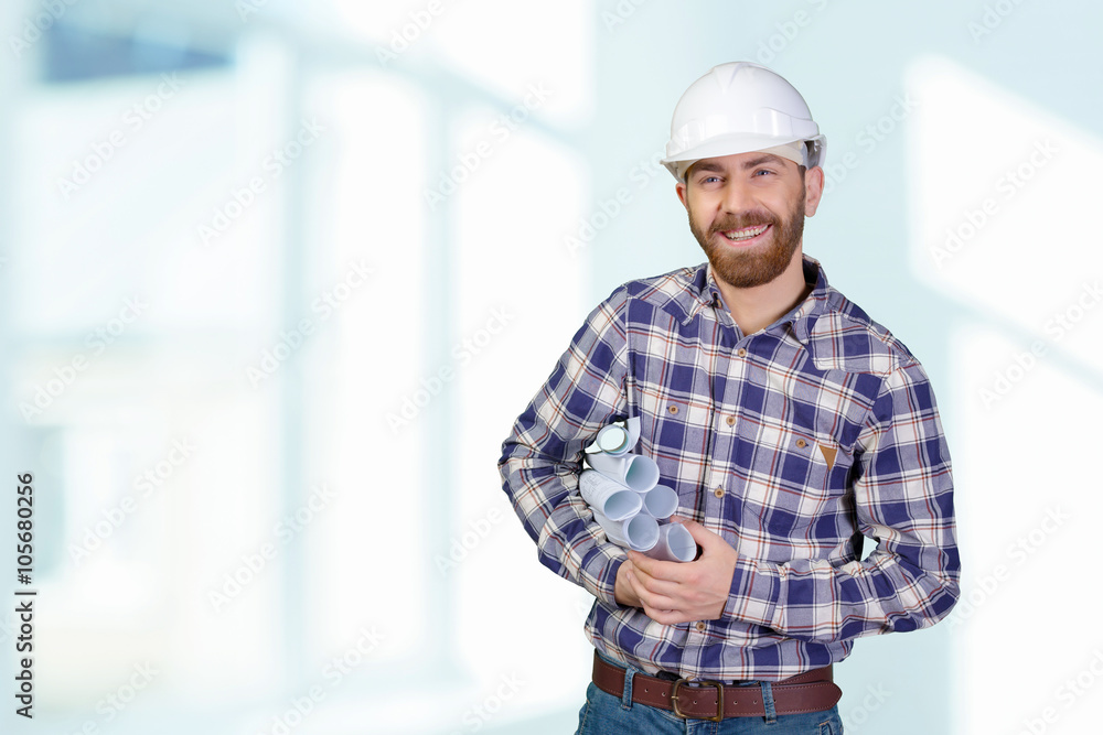 Young male engineer with helmet holding blueprints Young male engineer with helmet holding blueprints