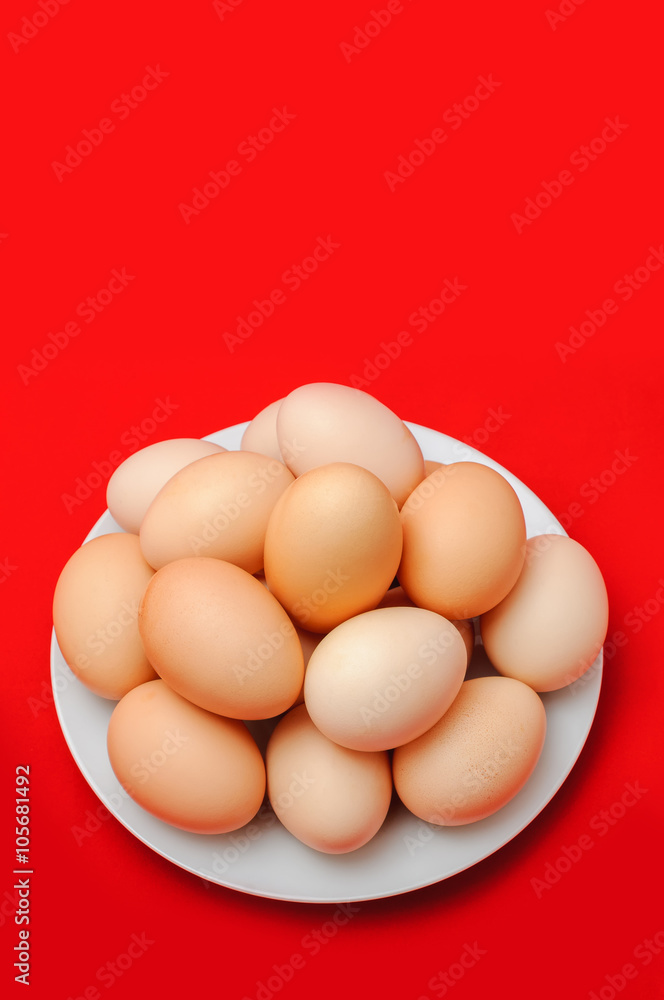 Eggs on a white plate on a red background.