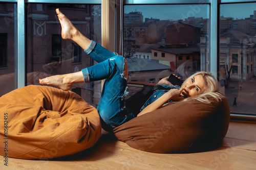 Young pretty blond woman posing on couch in casual jeans clothes