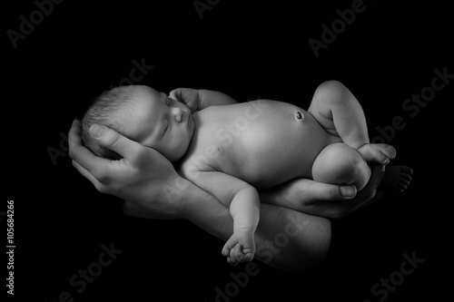 happy family , young parents holding a newborn baby in her arms and gently hugged him, black and white photo on a black background .