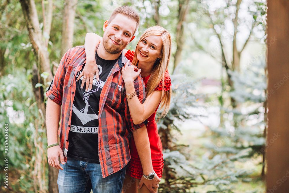 Young man and woman on the nature. Playful couple in love. Woman if red dress. Man in red shirt Young man and woman on the nature. Playful couple in love. Woman if red dress. Man in red shirt
