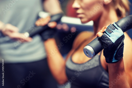 man and woman flexing muscles on gym machine