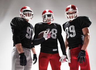 The three american football players posing with ball on white background