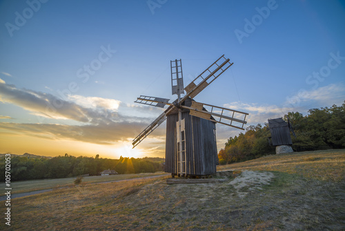 old windmill in a field at sunset