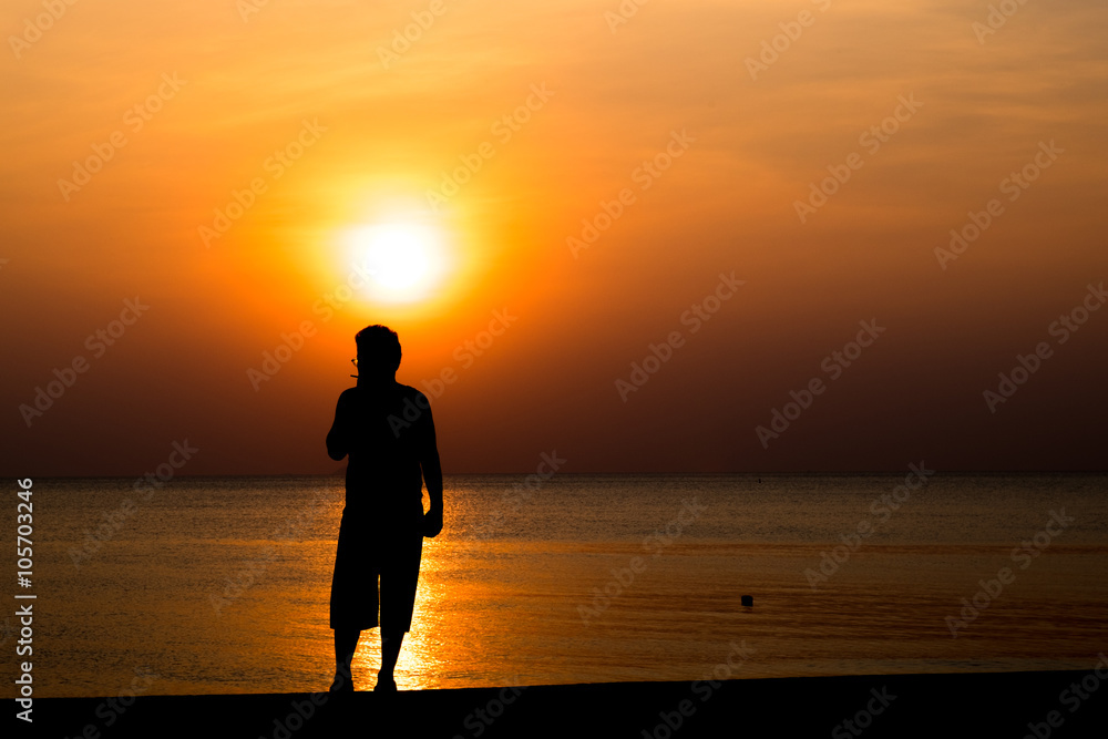 man smoking and sunset silhouette at the beach