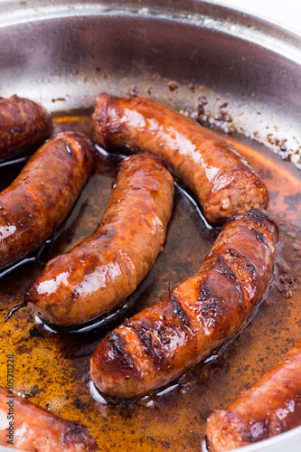 Homemade sausages frying in fat