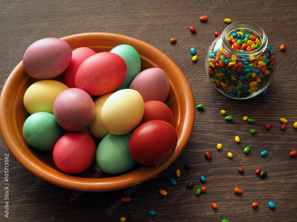 Fototapeta premium Plate with colorful Easter eggs and jar with colorful little candy