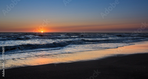 Touchdown, sun setting over and angry sea and waves, with a golden reflection on the beach © fungirlslim