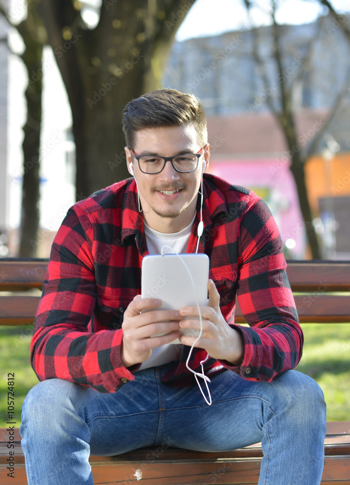 Young and handsome man with mobile tablet sitting in the park. Young and handsome man with mobile tablet sitting in the park.