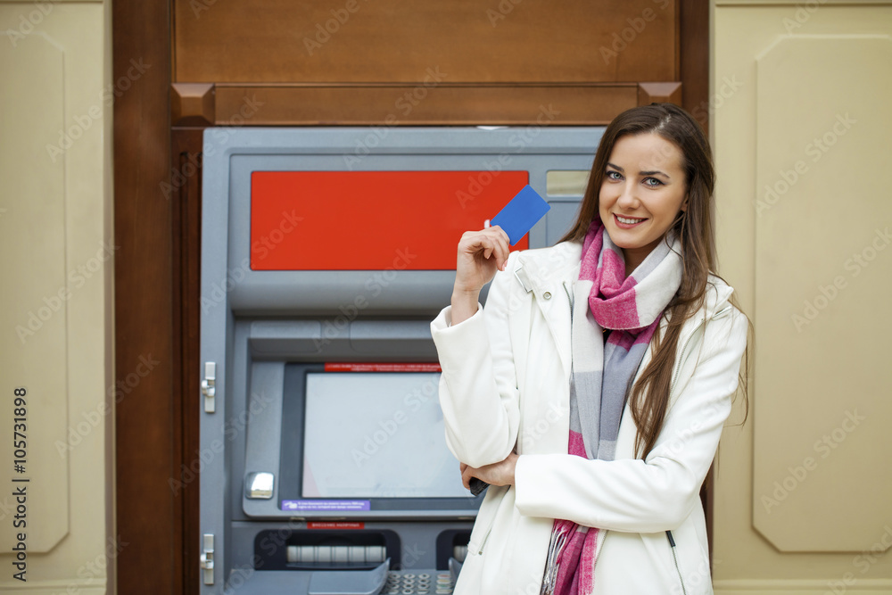 Young happy brunette woman withdrawing money from credit card at Young happy brunette woman withdrawing money from credit card at